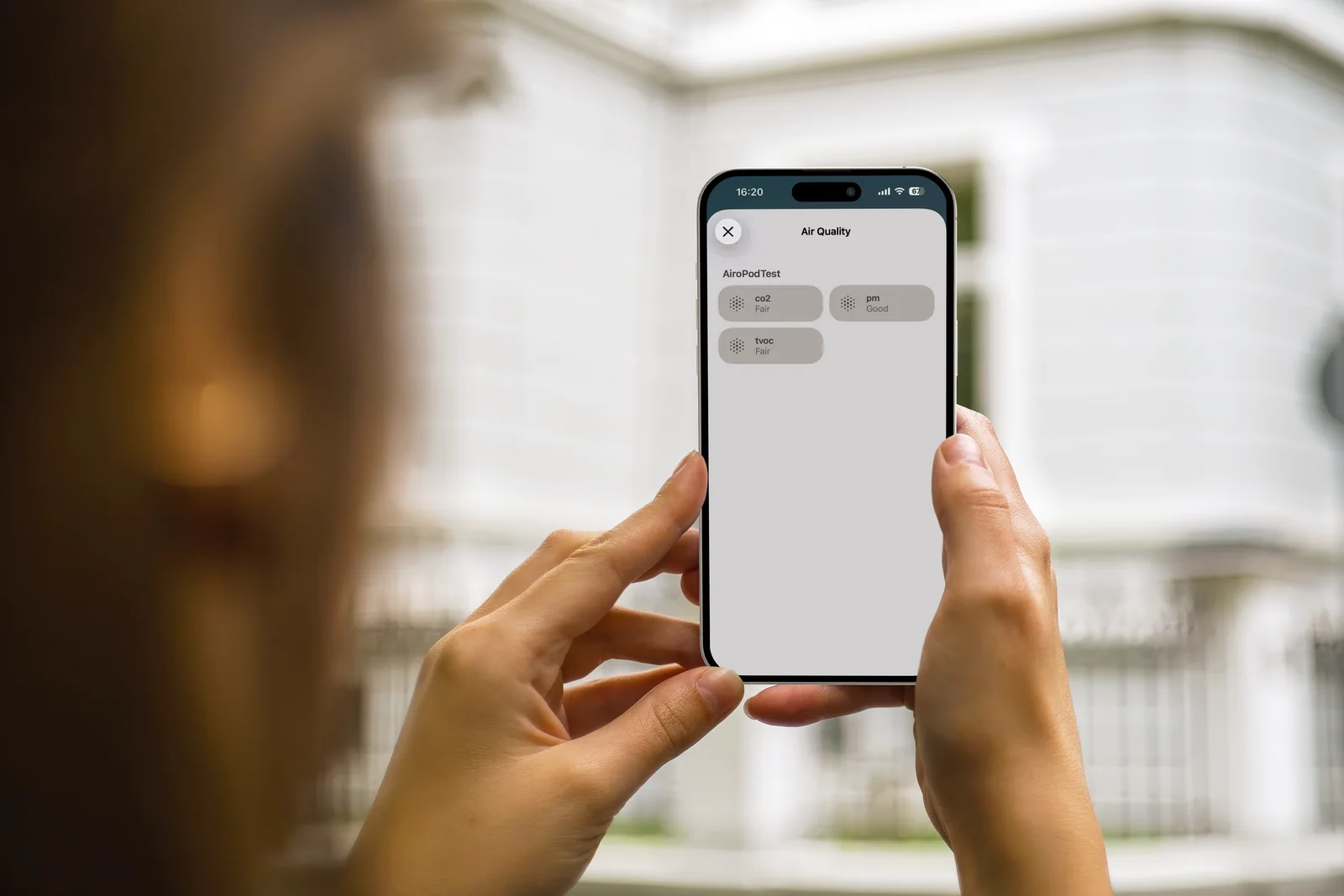 Hands holding an iPhone displaying Airo air quality readings in Apple Home