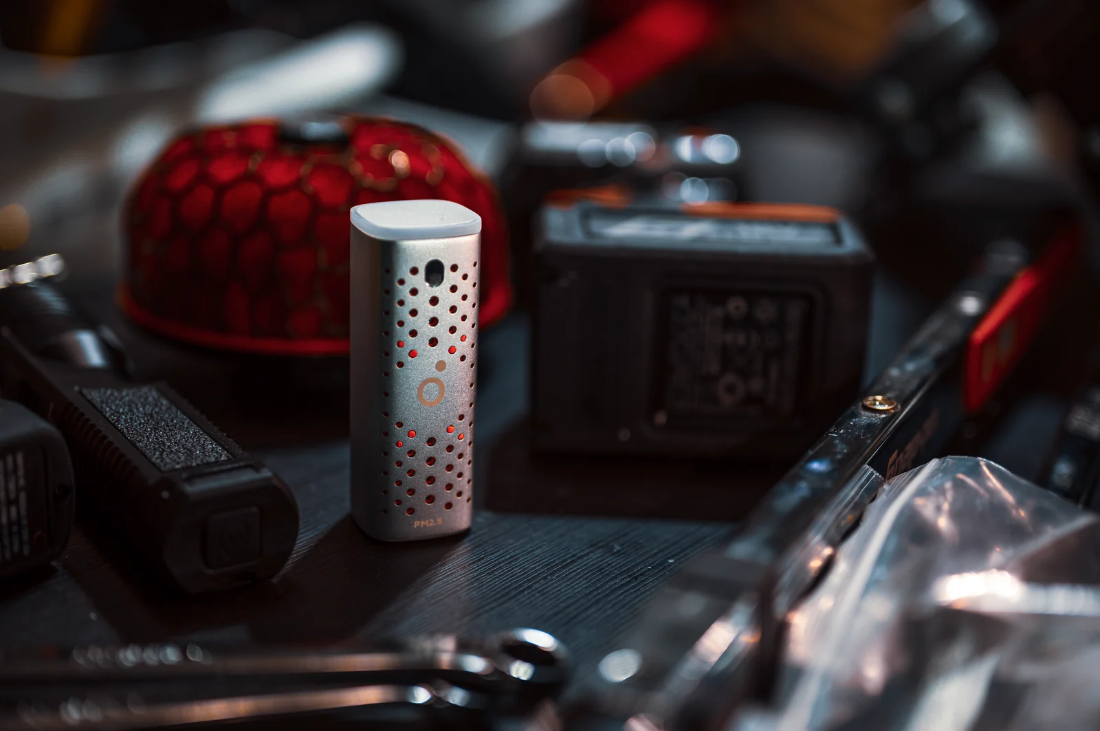 An Airo PM2.5 Pod standing among power-tool batteries, hand tools and workshop equipment.